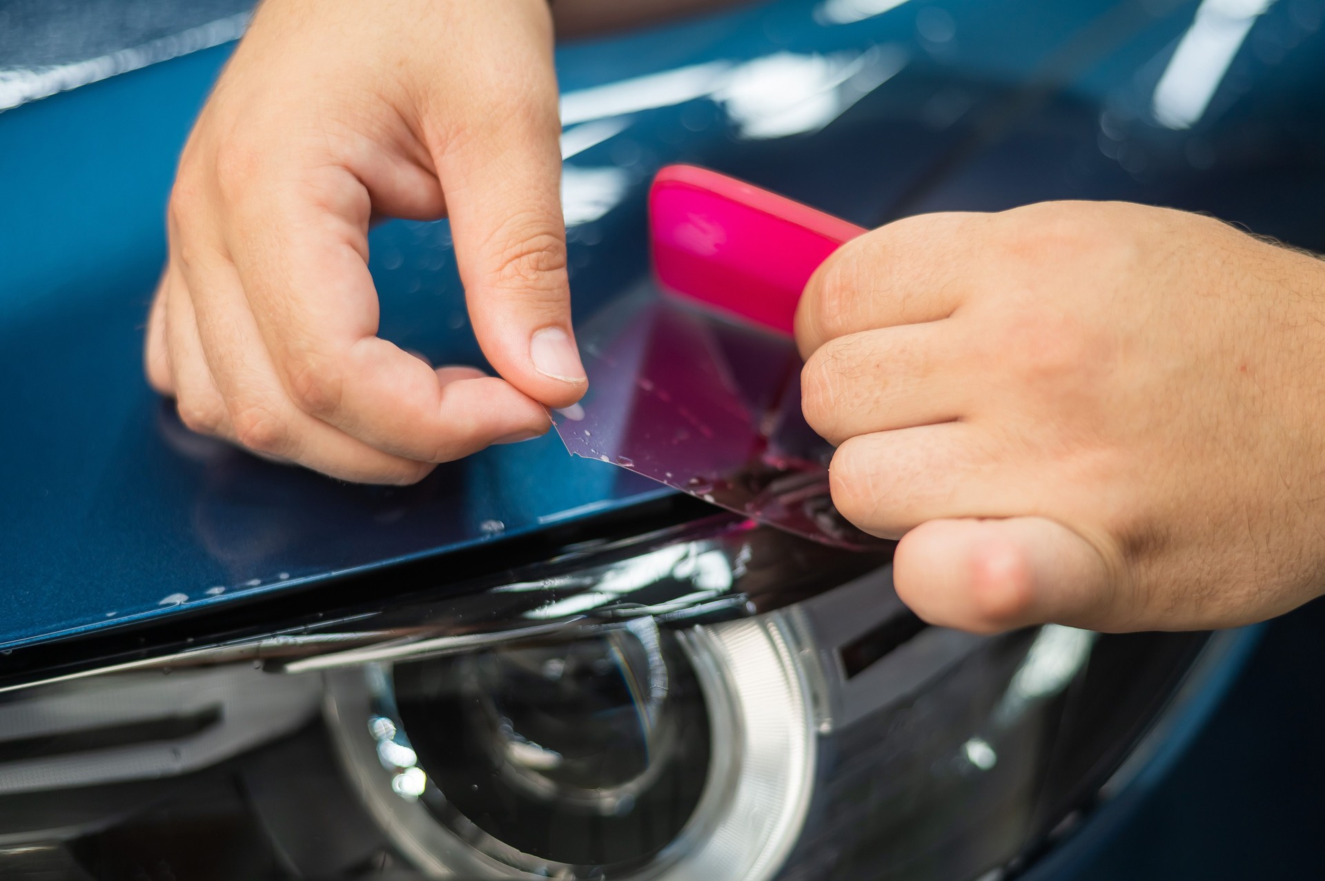 The master in the car service applies an armor film to the car.